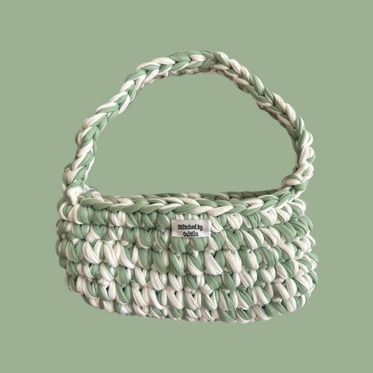 Mint green and white crocheted bag with a single shoulder strap at the top and a Stitched by Caitlin label on the front